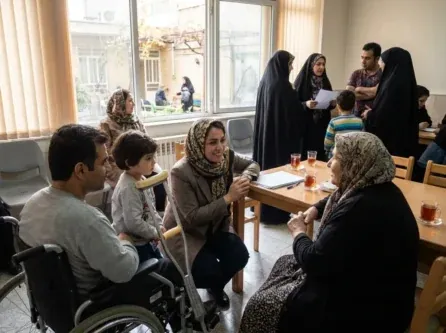 تصویری واقع‌گرایانه از یک مددکار اجتماعی ایرانی که در حال تعامل مهربانانه با افراد نیازمند، از جمله سالمندان یا کودکان، در یک محیط حمایتی است
